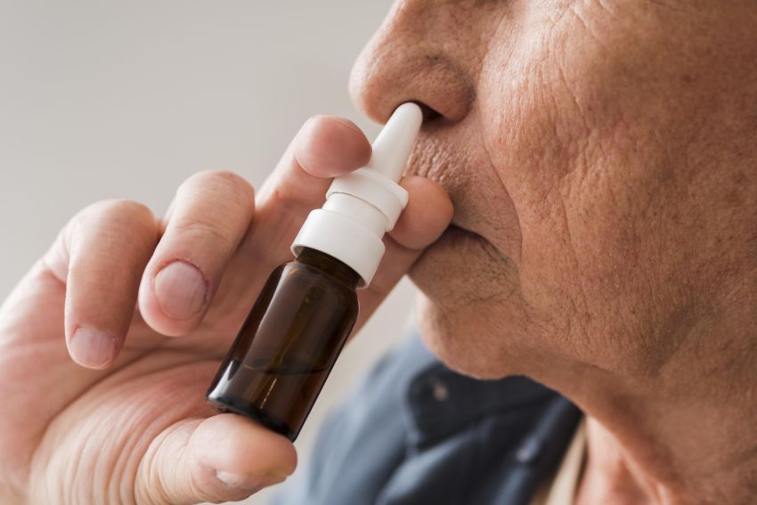 old man using nasal spray 