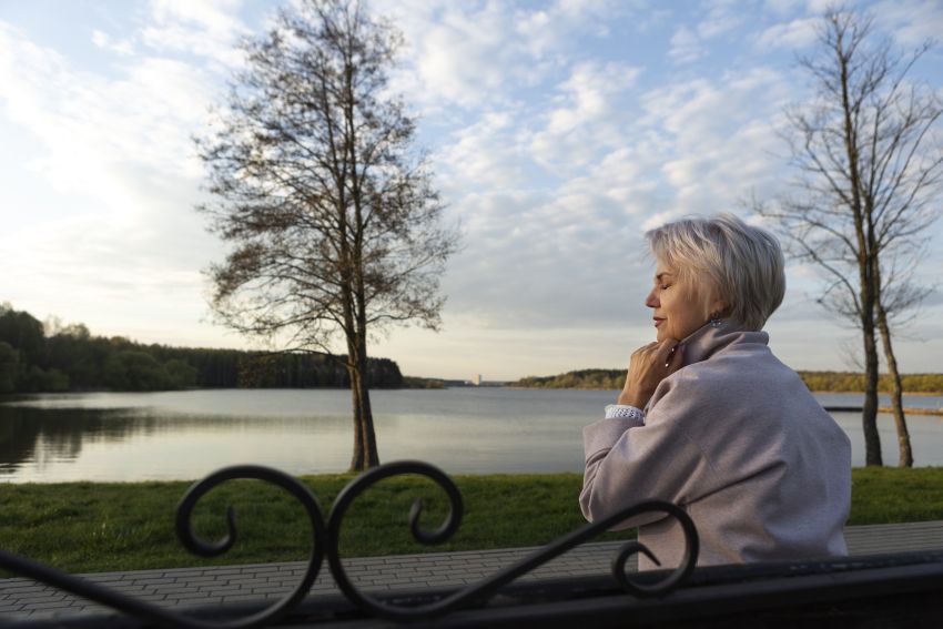 sad contemplative old woman near lake 