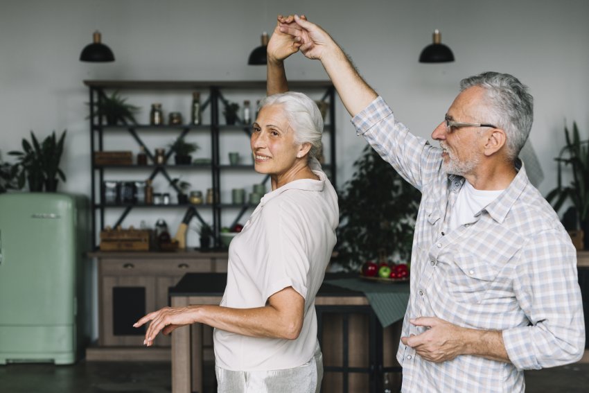 smiling senior couple dancing together kitchen