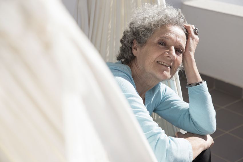 smiling senior woman lying hammock balcony